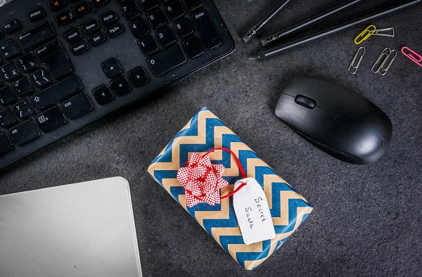 تصویر یک میز کار با موس و کیورد و دفتر که در کنار آن یک هدیه سازمانی شخصی سازی با یک پیام قرار دارد.