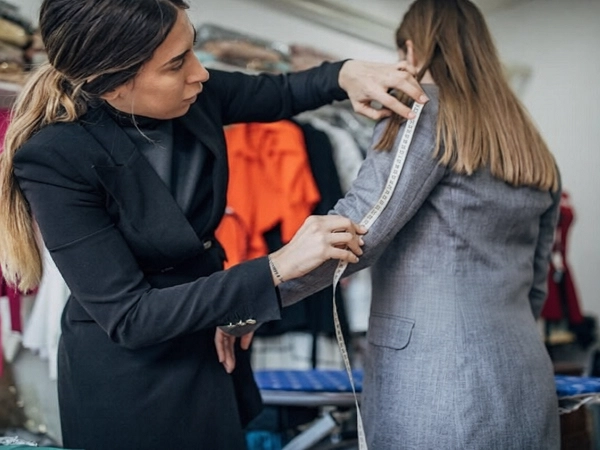 خانومی در حال اندازه گیری قد استین مانتو اداری خانوم دیگر